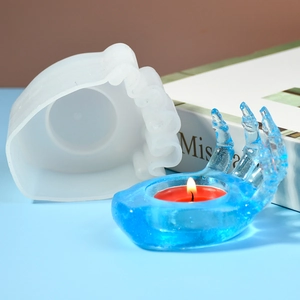 Detail of hand claw silicone mold and finished blue resin candle holder for Halloween DIY