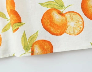 Makro-Detail von sommerlichem Orangen-Print auf weißem Leinenstoff mit sauberer Naht