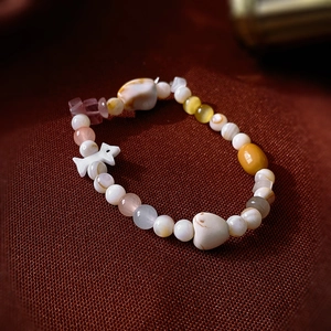 Gros plan du bracelet perlé macaron avec breloque éléphant sur tissu texturé sombre