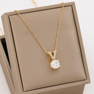 Elegant gold titanium steel necklace with V-letter zircon pendant on a jewelry box