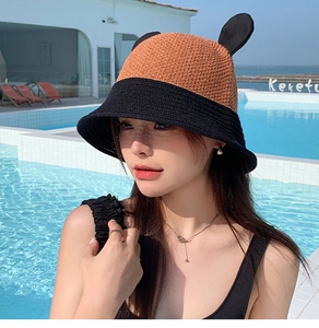 Close-up of black and orange woven straw bucket hat with decorative ears for sun protection
