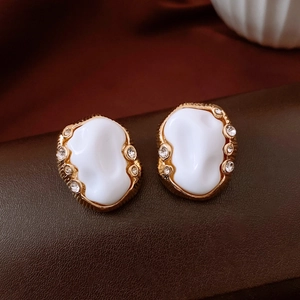 Macro view of vintage gold alloy earrings with white resin and sparkling zircons