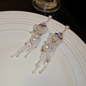 Macro detail of long tassel earrings with colorful crystals and pearl drop pendants
