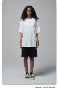 Clean detail of white oversize cotton t-shirt styled with black shorts and retro text