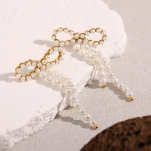 Detailed macro shot of vintage gold bow earrings with elegant dangling faux pearls