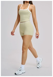 Detailweergave van olijfgroene yogaset met witte contrastbiezen op top en korte broek
