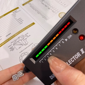 Diamond tester measuring moissanite stud earrings next to a professional certificate