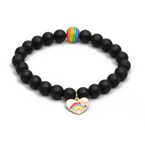 Rainbow beaded bracelet with matte black stones and colorful enamel heart charm on white background