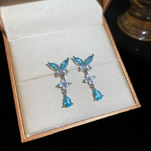 Dettaglio di orecchini d'argento con pietre a goccia blu e fiori in zircone bianco