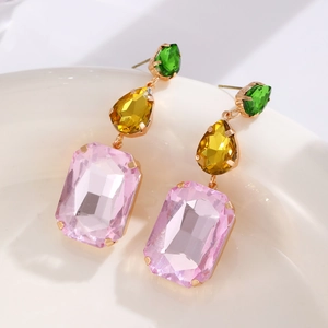 Close-up of dangling earrings with pink, yellow, and green teardrop crystals in gold
