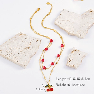 Detail showing the double-layer golden chain with red beads and cherry pendant