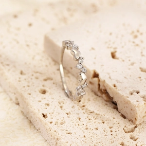 Macro shot of silver S925 heart ring with diamonds placed on a textured beige stone