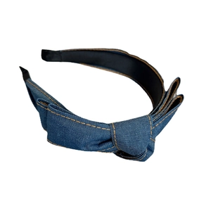 Denim bow headband for women with orange stitching and knotted fabric design on white background