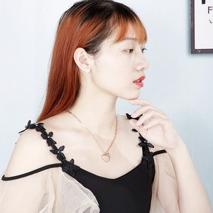 Gros plan d'un collier cœur doré rose et de boucles d'oreilles portés par un mannequin