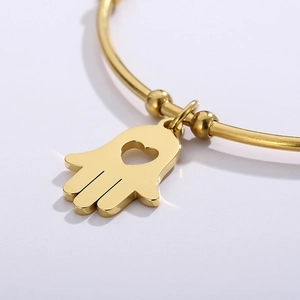 Gold stainless steel Hamsa hand open bangle featuring a heart cutout pendant charm