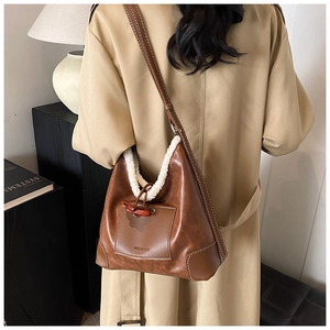 Detail of winter bucket bag featuring fuzzy faux shearling trim and horn buckle closure