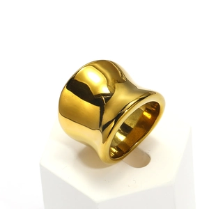 Detailed view of wide gold polished stainless steel ring on a white geometric stand