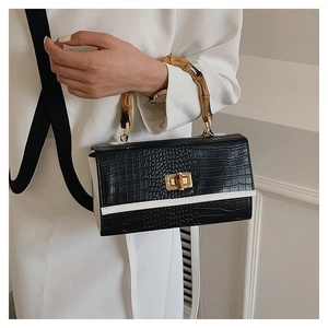 Detailed view of the bamboo handle and golden twist lock on the black faux croc tote bag