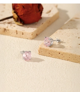 Macro shot of S925 sterling silver studs with pink gemstone on a travertine stone