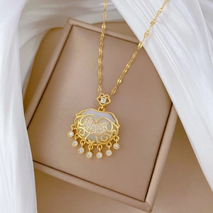 Macro detail of luxury gold tassel lock necklace with pavé diamonds in a jewelry box