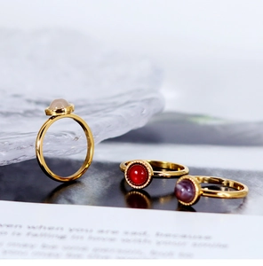 Detailed view of three 18K gold plated rings with red, purple and white gemstones