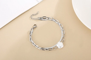 Detail of silver double-layered snake and paperclip chain bracelet with shell flower charm