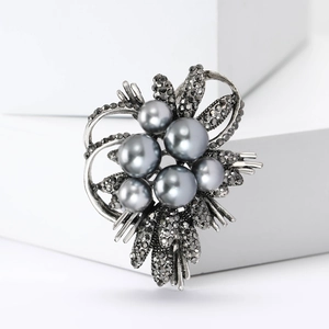 Detailed close-up of elegant pearl and black rhinestone flower brooch on white cubes