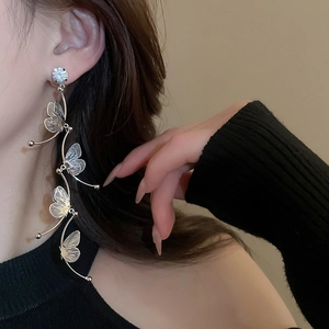 Close-up of elegant silver butterfly tassel earrings with rhinestones on a female model