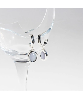 Dettaglio di orecchini ovali in argento con intarsio azzurro appesi al vetro