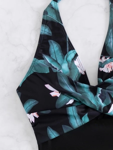 Detail shot of halter neck swimwear featuring tropical green leaf and pink floral prints