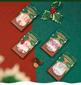Detail of Christmas press-on nails with snowflake and glitter designs in green packaging