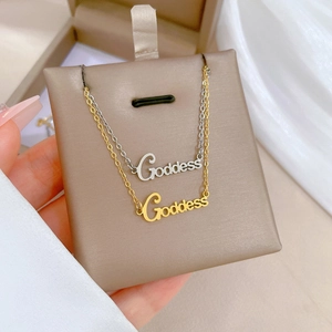 Detail of Goddess letter necklaces in gold and silver finish on a display card