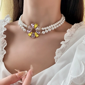 Detail einer eleganten zweilagigen Perlenkette mit violettem Blumenanhänger am Model