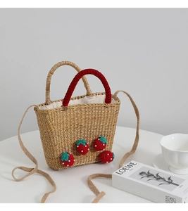 Détail du sac en paille fait main avec fraises au crochet et poignée en velours rouge