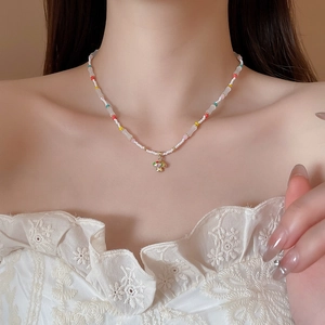 Detail of beaded necklace with a golden mushroom pendant worn on a female model