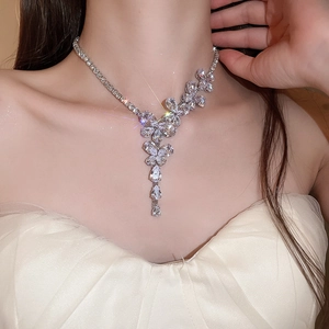 Dettaglio della collana con nappine a farfalla scintillante indossata dal modello