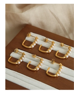 Detailed macro view of three pairs of C-shaped gold-plated earrings with pearls