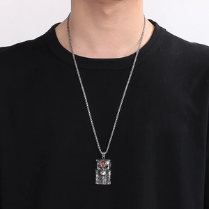 Detail of gothic stainless steel pendant with skull relief and a red stone eye accent