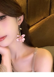 Detailed view of pink floral drop earrings with golden stem hooks worn by a model