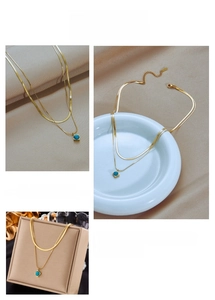 Detail of double-layer gold chain necklace featuring a square turquoise stone pendant