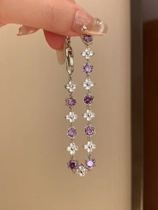 Detail of silver bracelet featuring hexagonal purple gems and zircon flower accents