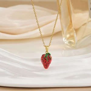 Macro view of gold-plated chain and red enamel strawberry pendant necklace for women