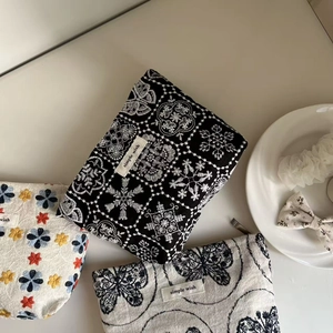 Detailed flat lay of small embroidered canvas pouches with floral patterns and woven labels