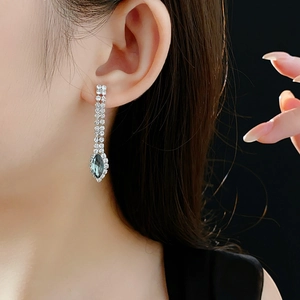 Detail of silver drop earrings with teal teardrop gemstone and sparkling rhinestones