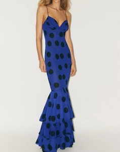 Close-up of blue polka dot spaghetti strap dress featuring a tiered mermaid hemline