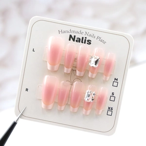 Detail view of French ombre nude nails with sparkling rhinestones and white tips