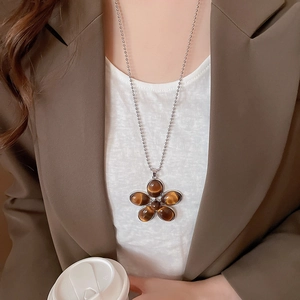 Detail view of flower pendant necklace with tiger eye stones worn by a model