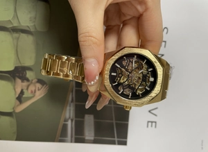 Detailed close-up of golden octagonal mechanical watch with a black skeleton dial face