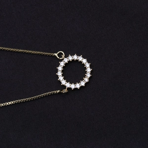 Nahaufnahme der goldenen Halskette mit funkelndem, zirkonia-besetztem Ring-Anhänger im Detail