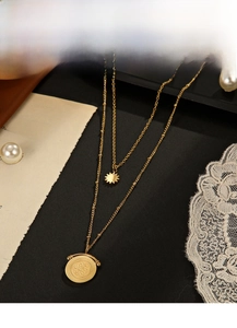 Detail of layered gold coin necklace with sunburst star pendant on vintage newspaper background